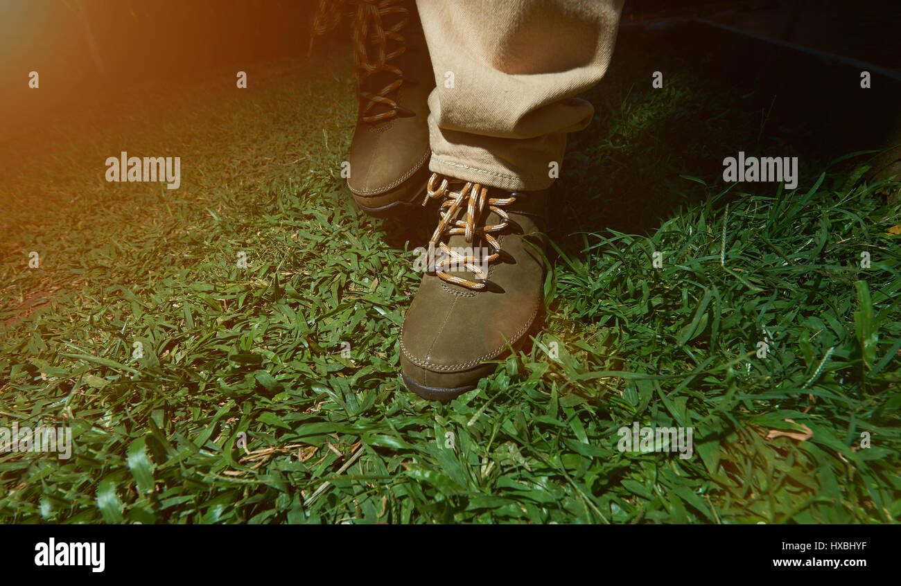 Fase di lavorazione su erba verde in marrone scarpe. Avventura escursionismo close-up Foto Stock