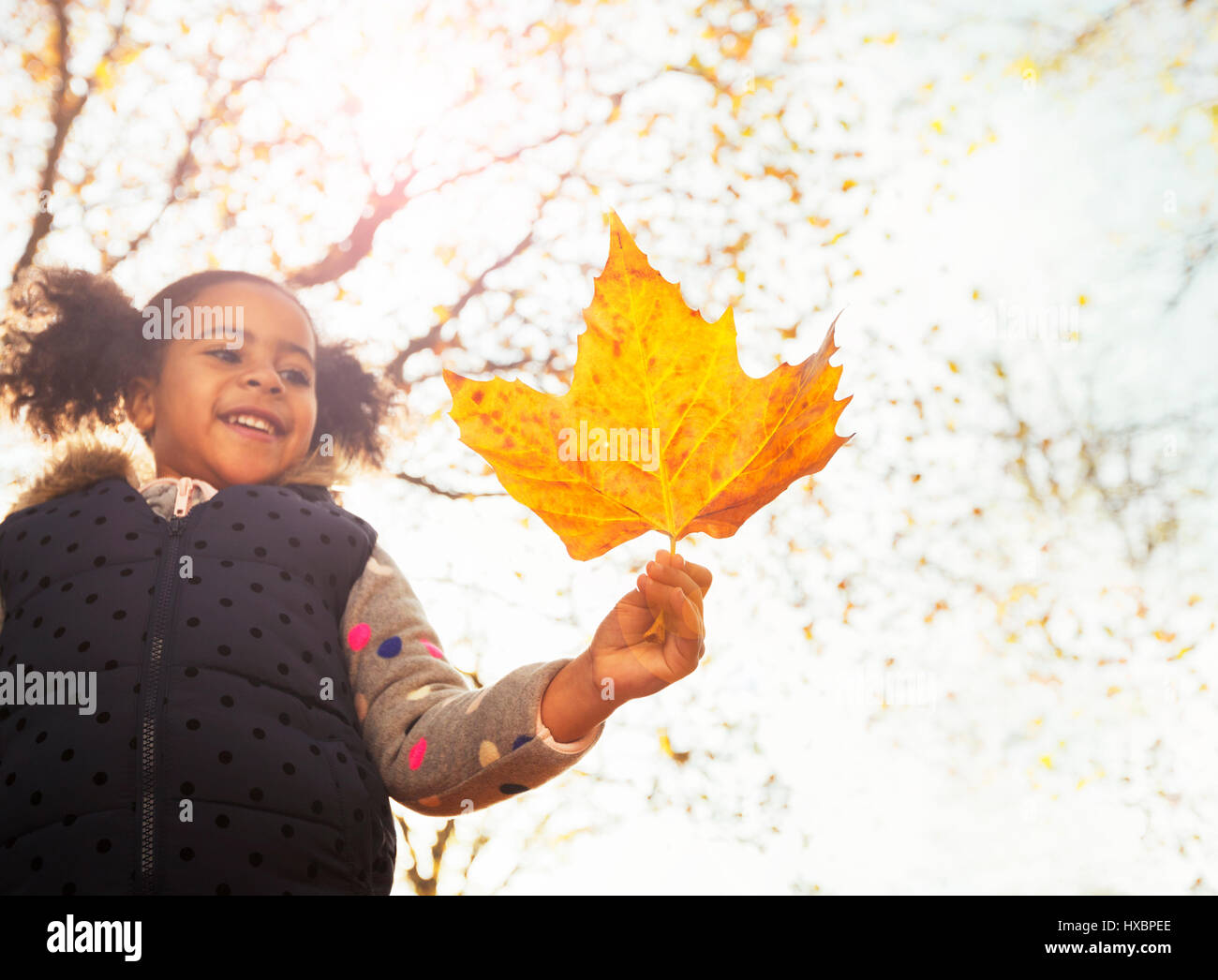 Sorridente ragazza con orange Foglia di acero in autunno soleggiata park Foto Stock