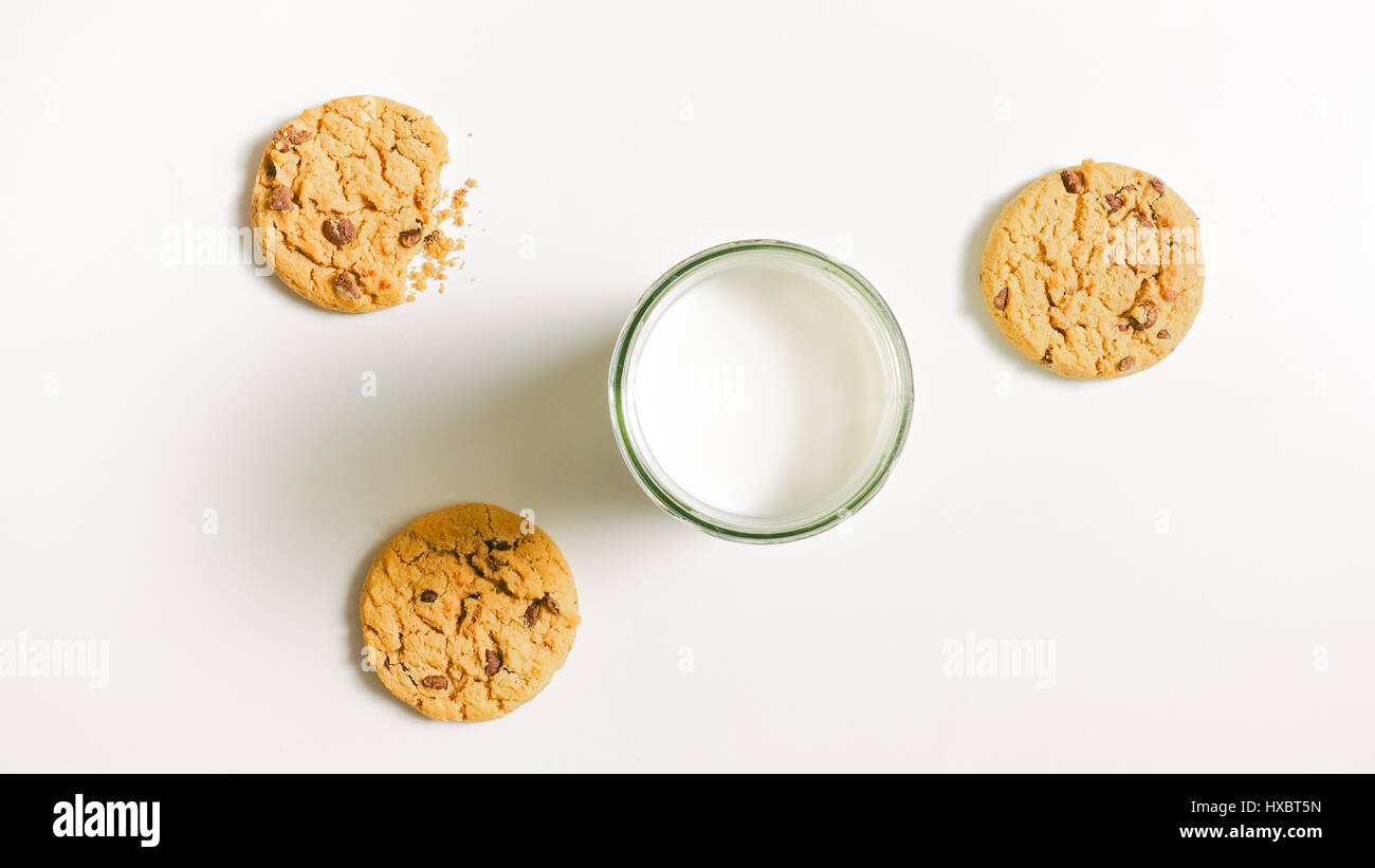 Tre round friabili biscotti e con un bicchiere pieno di latte sul tavolo. Un cookie è una pungente Foto Stock
