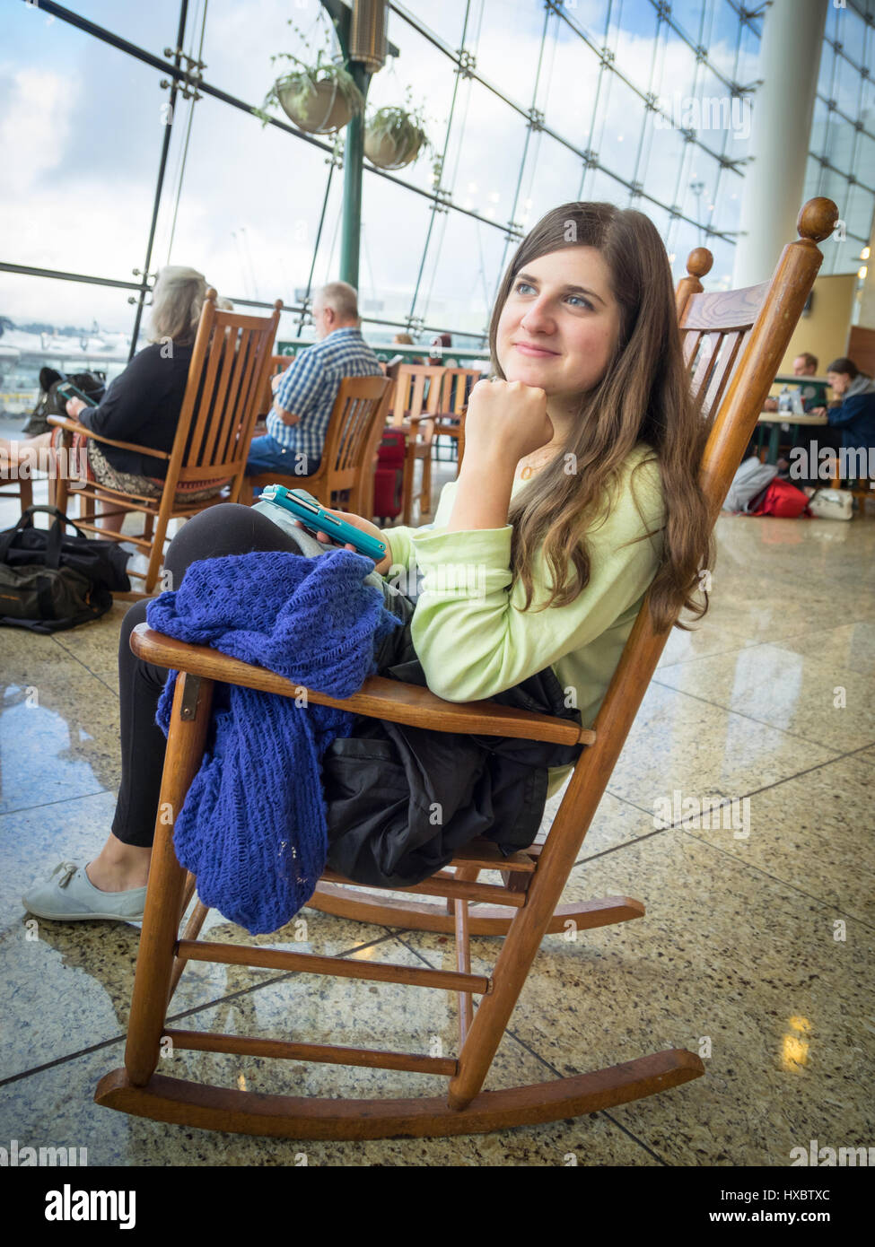 Una ragazza si siede su una sedia a dondolo nel Pacifico Mercatino del terminale centrale dell'Aeroporto Internazionale di Seattle-Tacoma (aeroporto Sea-Tac). Foto Stock