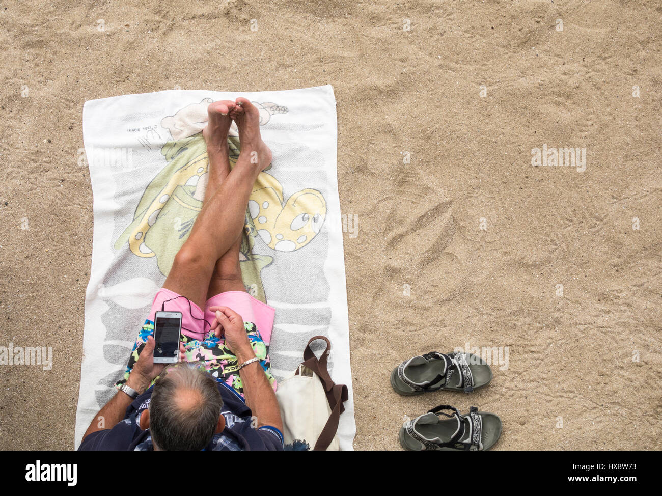 Uomo anziano utilizzando il telefono cellulare sulla spiaggia Foto Stock