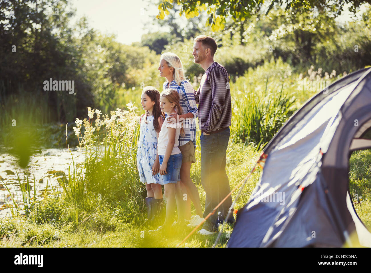 La famiglia a sunny campeggio lakeside guardando lontano Foto Stock