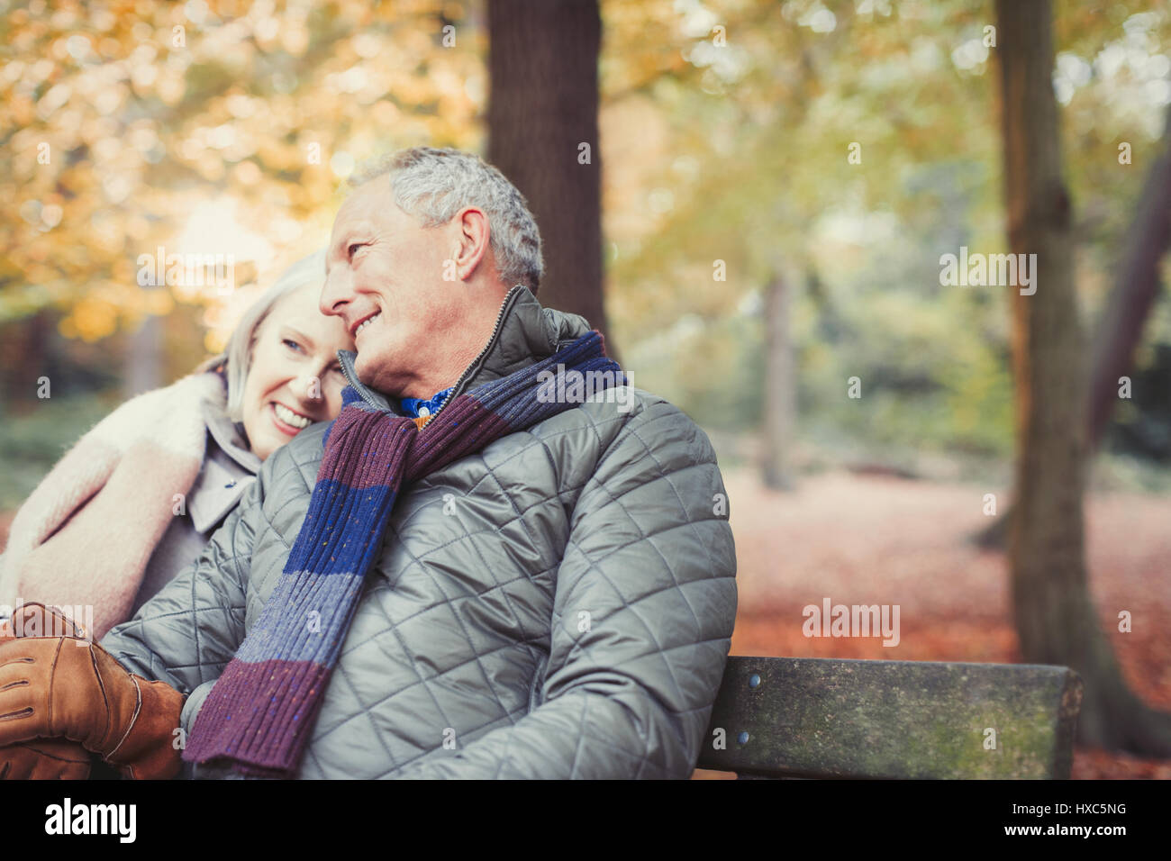Affettuosa coppia senior sul banco di lavoro in autunno park Foto Stock