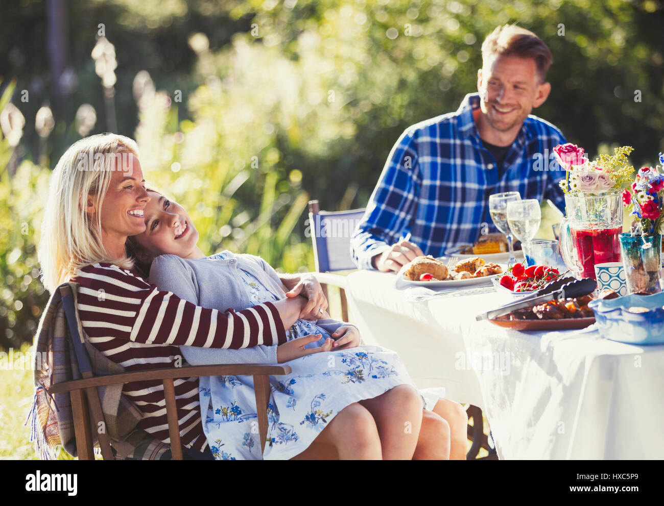Sorridente famiglia affettuosa godendo il pranzo al giardino soleggiato patio partito tabella Foto Stock