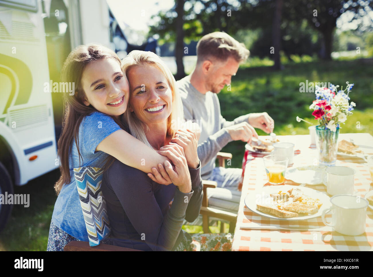 Sorridente e affettuosa Madre e figlia costeggiata a tavola al di fuori di sunny motor home Foto Stock
