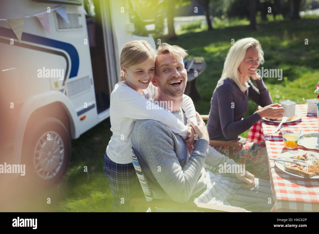 Felice, padre affettuoso e la figlia che abbraccia esternamente sunny motor home Foto Stock