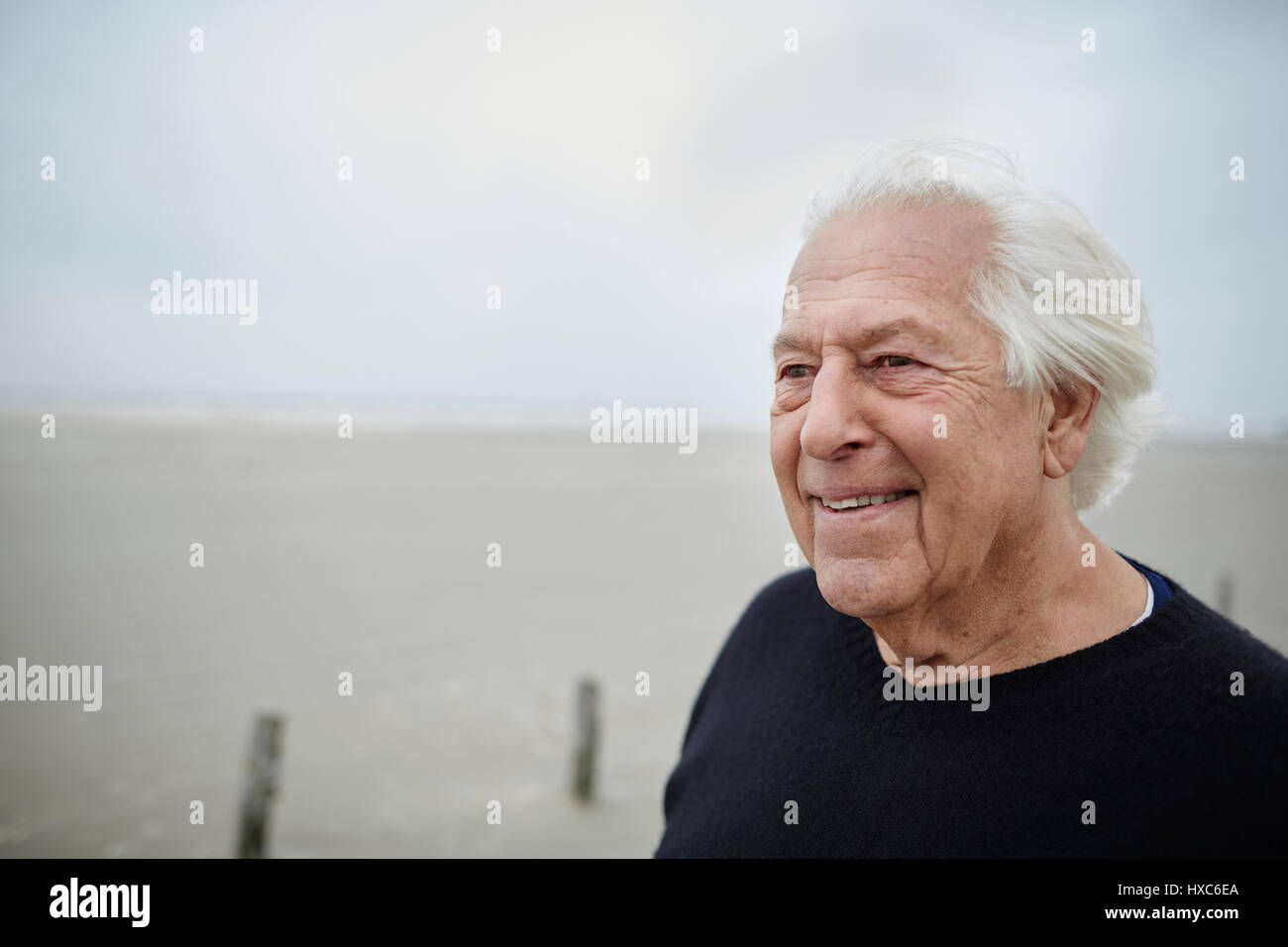 Senior sorridente uomo che guarda lontano sulla spiaggia Foto Stock