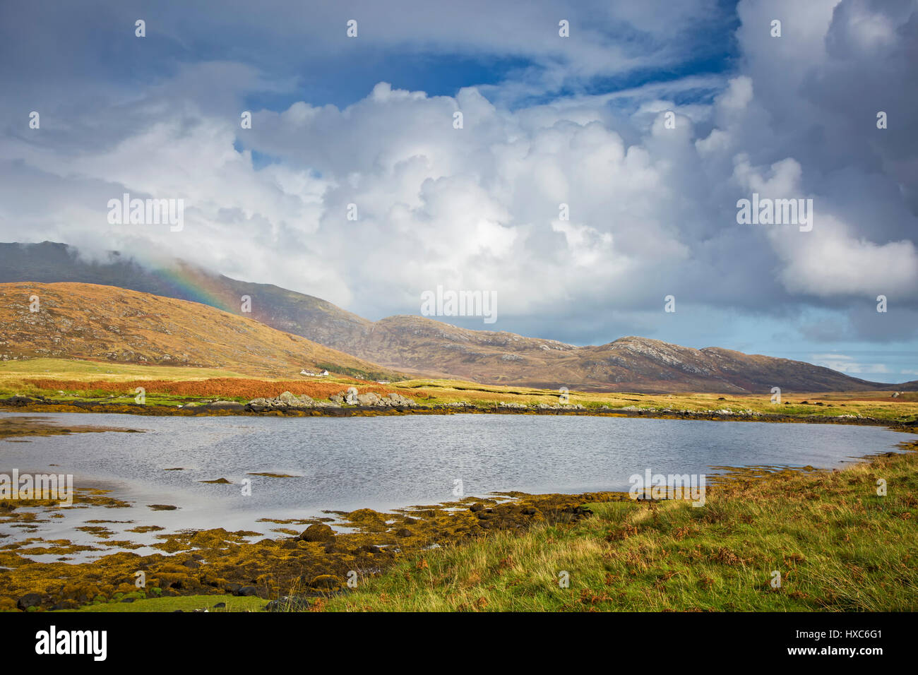 Vista tranquilla nuvole e rainbow su dolci colline oltre il lago di Loch Aineort, Sud Uist, Ebridi Esterne Foto Stock