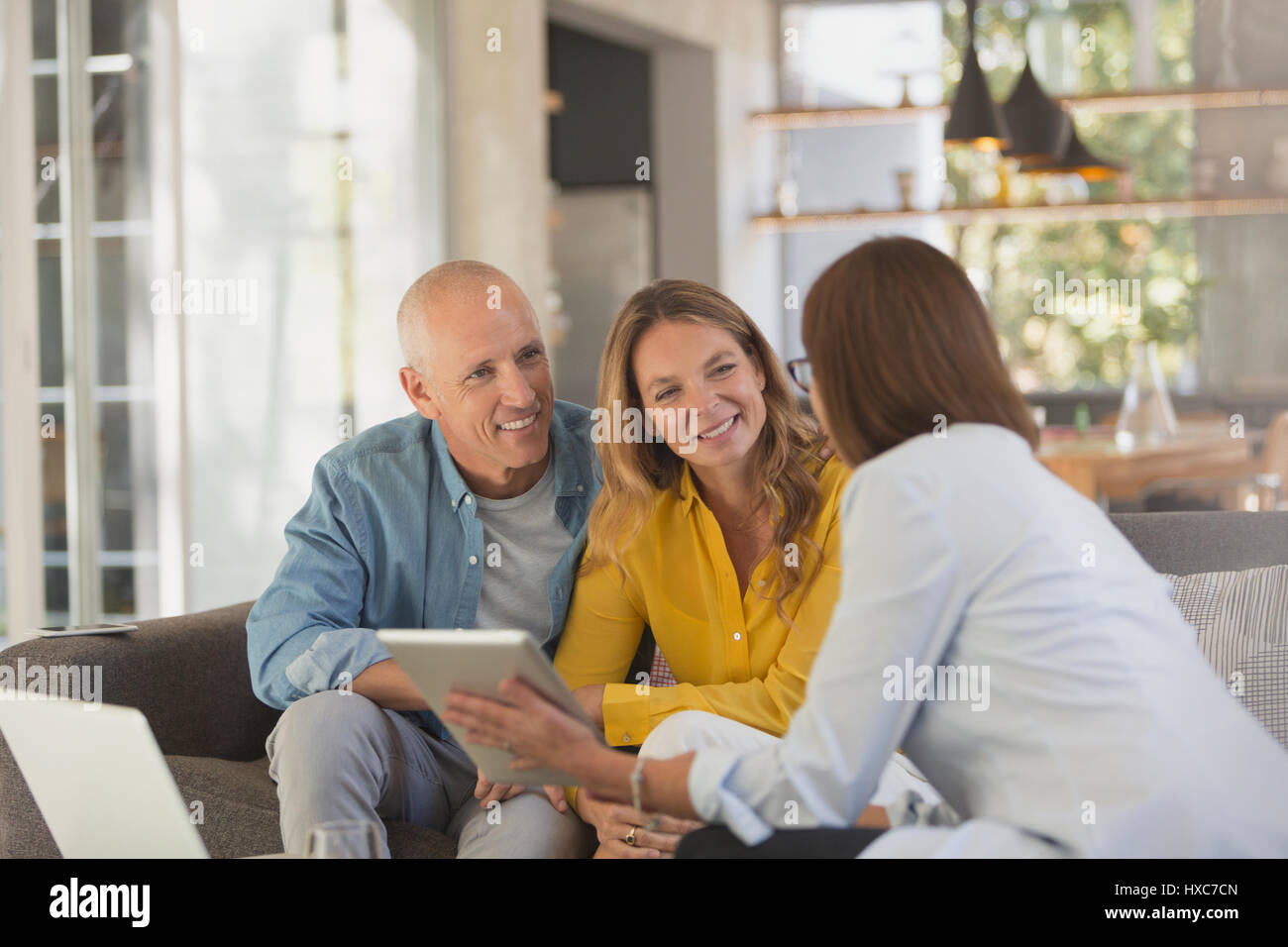 Advisor finanziario con tavoletta digitale incontro con il giovane nel soggiorno Foto Stock