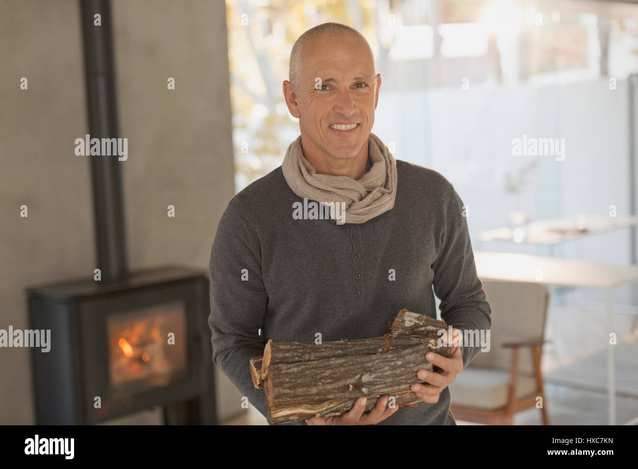 Ritratto sorridente uomo maturo holding di legna da ardere davanti al caminetto a legna Foto Stock