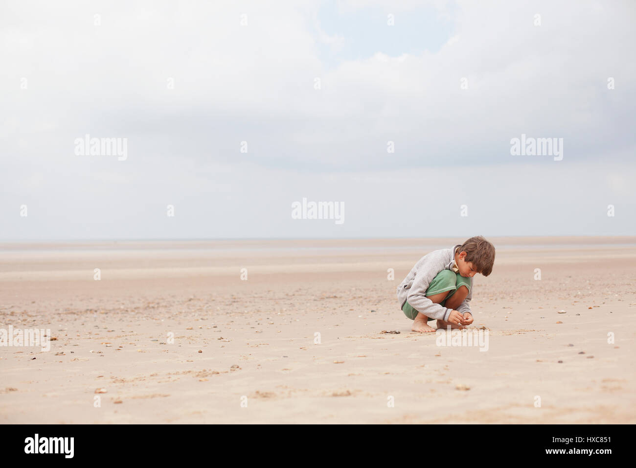 Ragazzo giocando in sabbia sulla cortina di nubi estate spiaggia Foto Stock