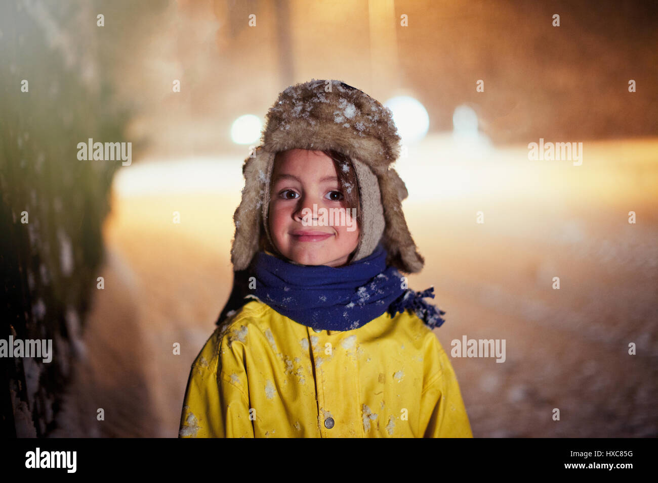 Ritratto sorridente ragazzo in abiti caldi in piedi in strada innevata Foto Stock