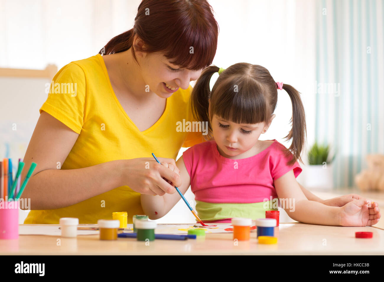 Carino madre insegnare a sua figlia kid per la verniciatura Foto Stock