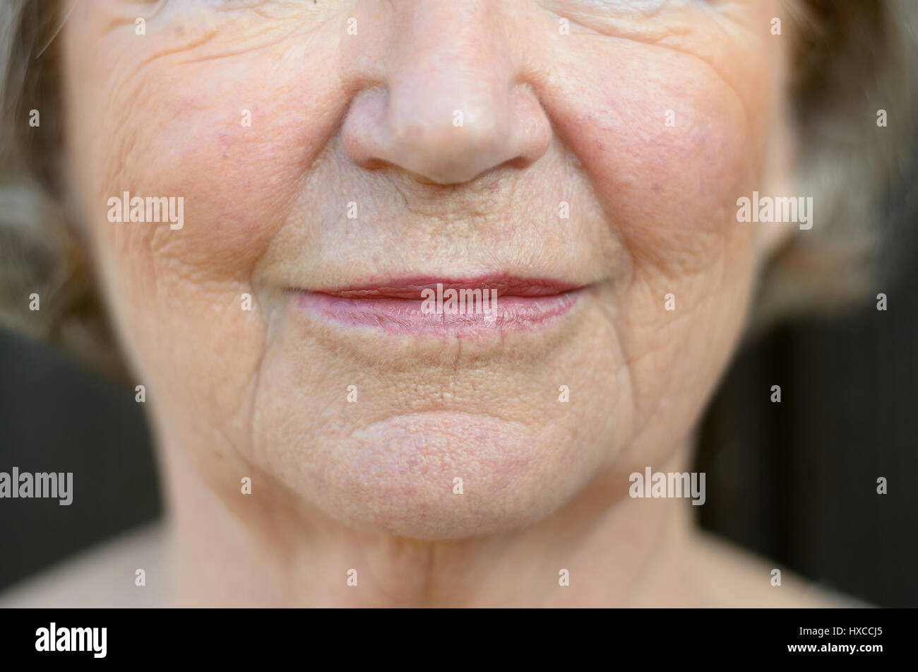 Primo piano sulla bocca di un senior donna bionda con la sua bocca chiusa e una espressione seria Foto Stock
