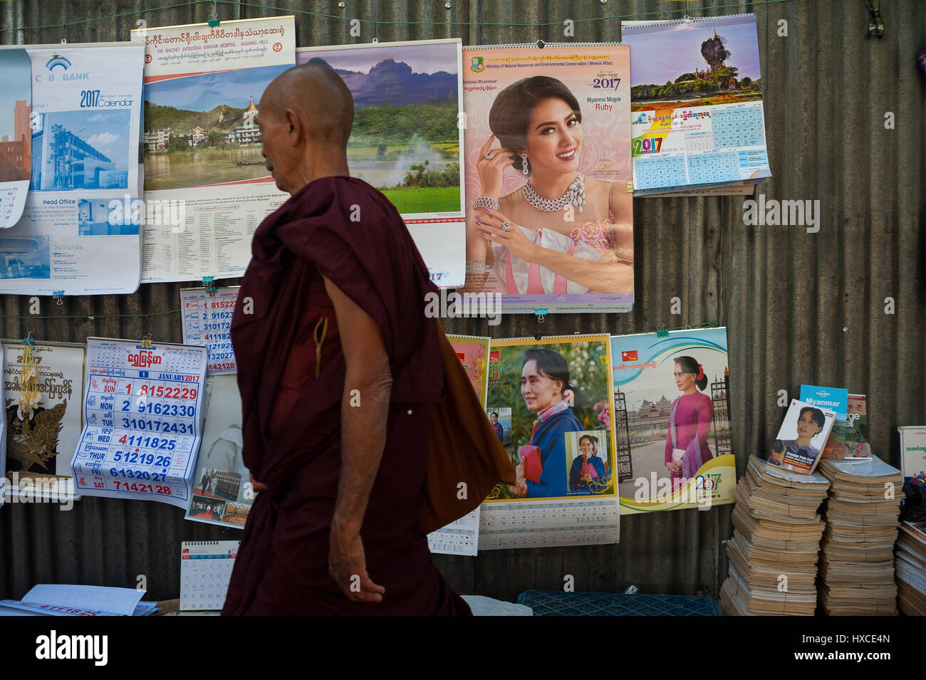 26.01.2017, Yangon, repubblica dell' Unione di Myanmar, asia - un monaco buddista passeggiate da un venditore ambulante che vende le calandre e poster. Foto Stock