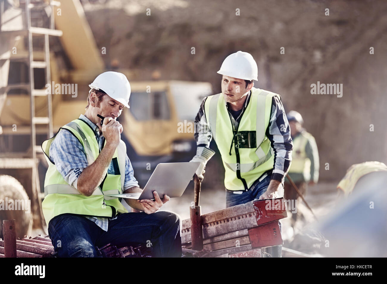 Caposquadra e lavoratore edile utilizzando il portatile in sito in costruzione Foto Stock
