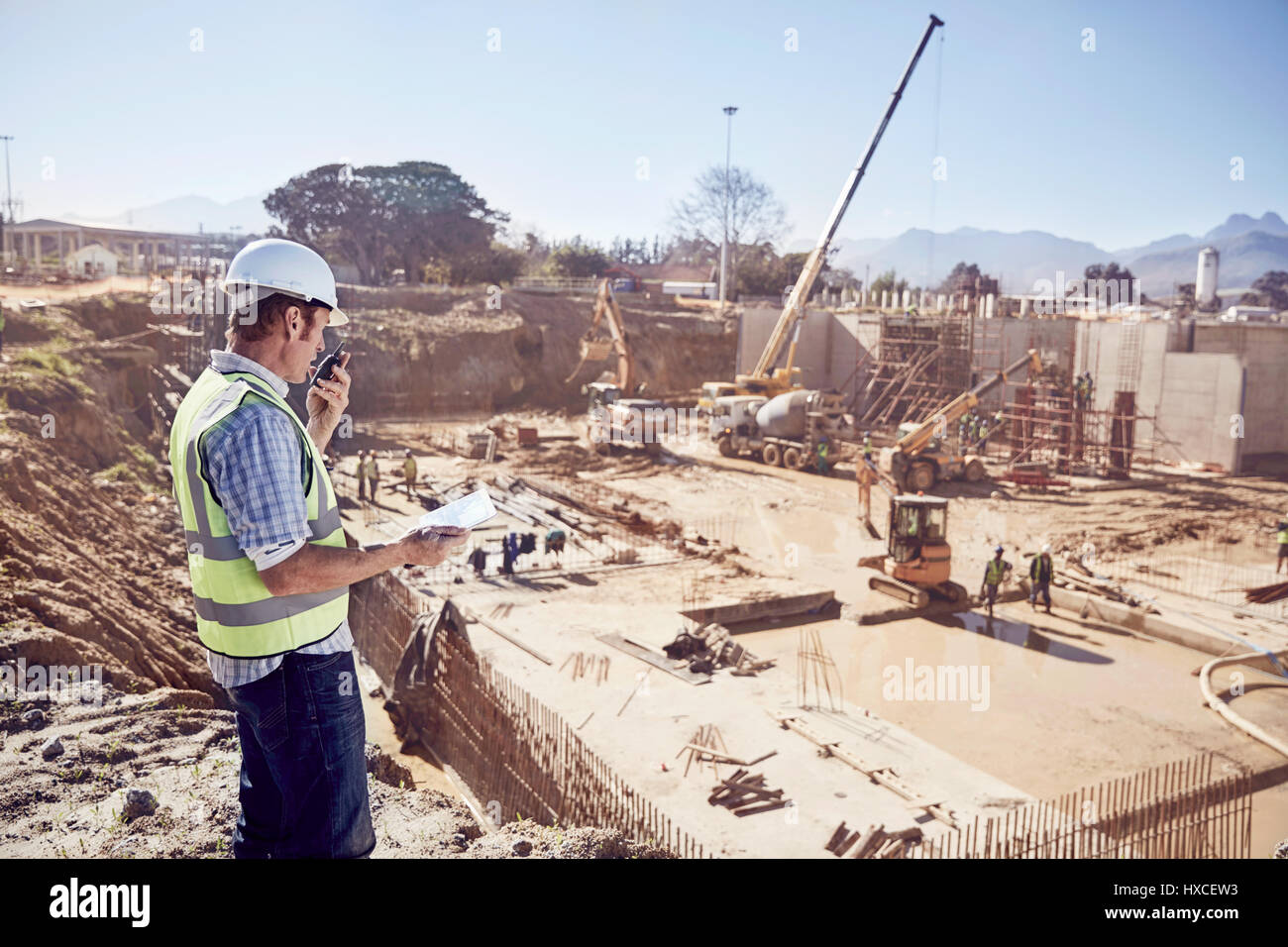 Operaio edile foreman utilizzando un walkie-talkie a sunny sito in costruzione Foto Stock