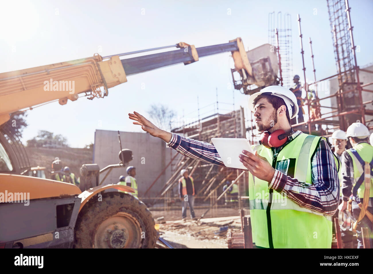 Operaio edile foreman con tavoletta digitale attrezzature di guida a sunny sito in costruzione Foto Stock