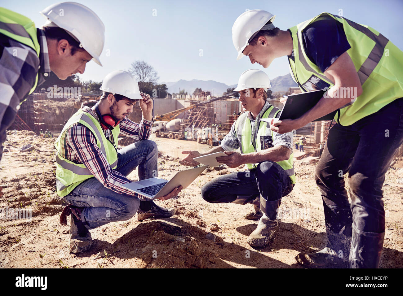 Lavoratori edili e ingegneri usando compresse digitale a sunny sito in costruzione Foto Stock