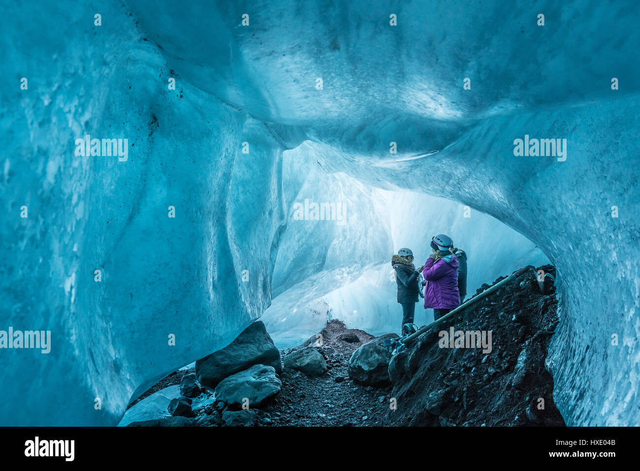 Turisti in una caverna di ghiaccio sotto un ghiacciaio in Islanda Foto Stock