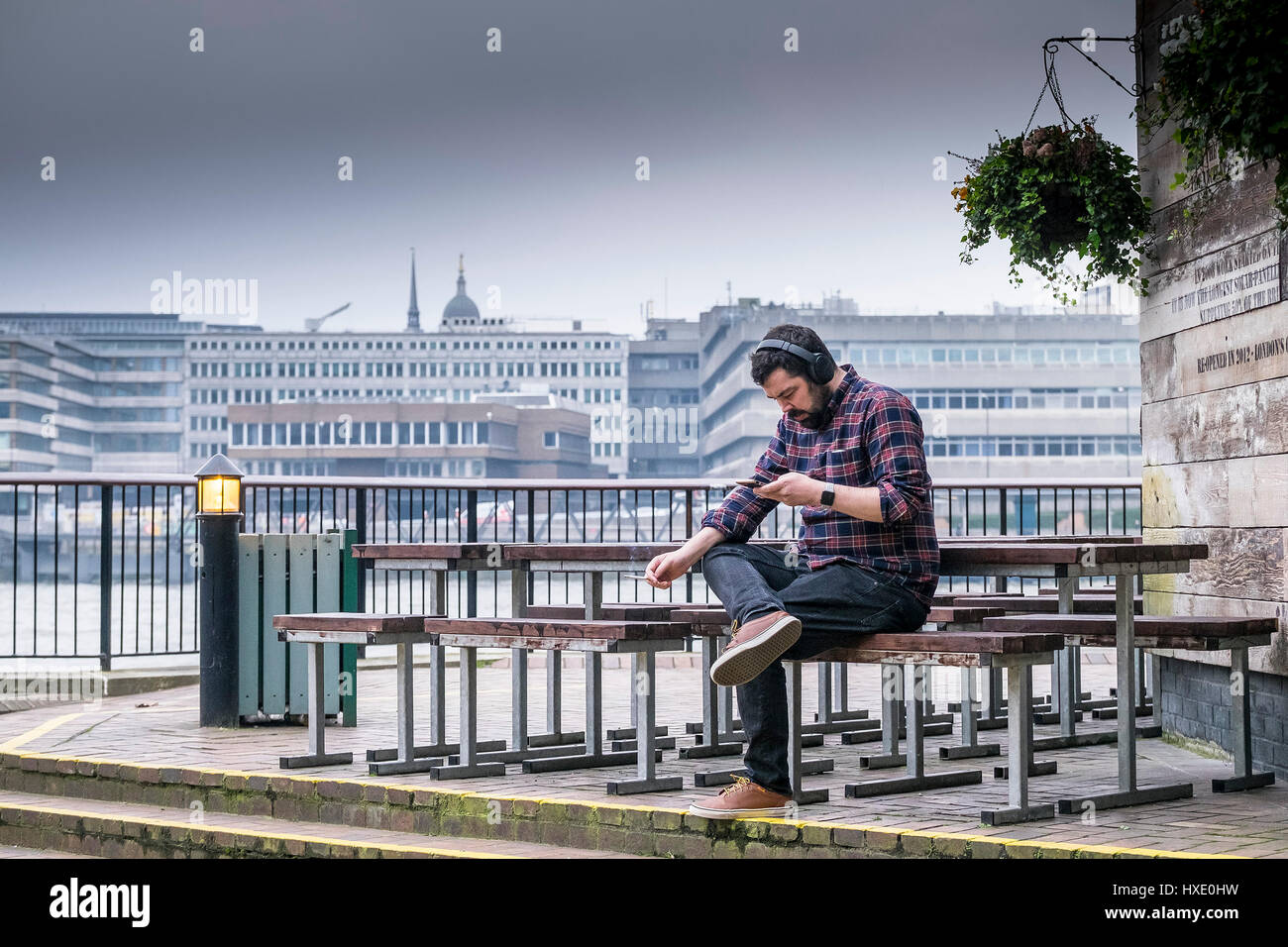 Uomo seduto di piacere di fumare auricolari rilassamento rilassante Londra Foto Stock