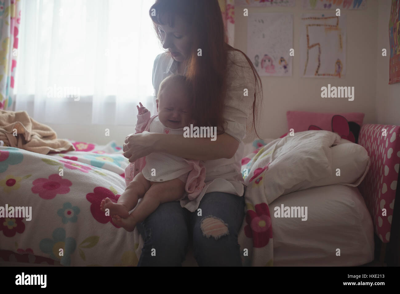 Madre con Gridando bambino seduto sul letto di casa Foto Stock