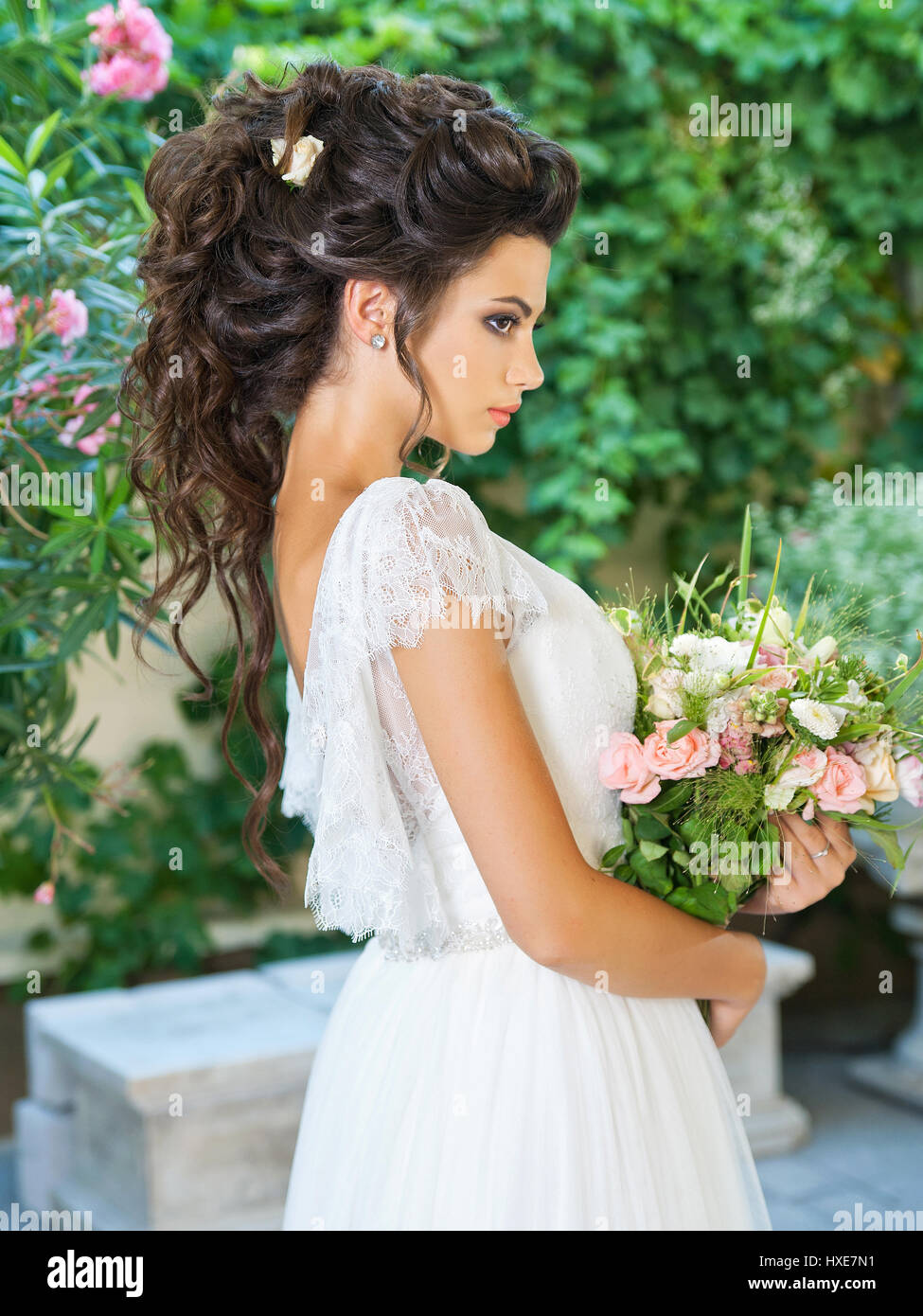 Bella sposa in un abito da sposa con un bouquet Foto Stock