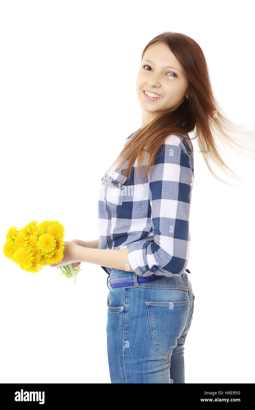 Ragazza vestita in jeans e una maglietta scozzese, detiene un giallo fiori selvatici. Ragazza con bouquet di tarassaco. Una persona, aspetto caucasico, marrone capelli, te Foto Stock