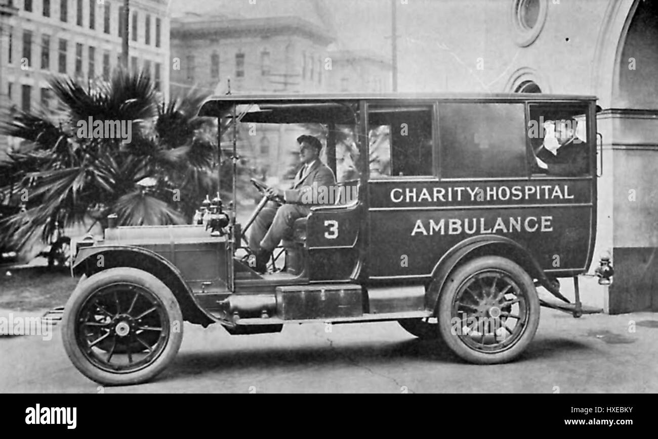 Alcuni uomini fate una corsa in una ambulanza motorizzati veicolo con il testo sul lato di lettura OSPEDALE DI CARITÀ ambulanza, vicino la Louisiana carità Hospital di New Orleans, Louisiana, 1912. Foto Stock