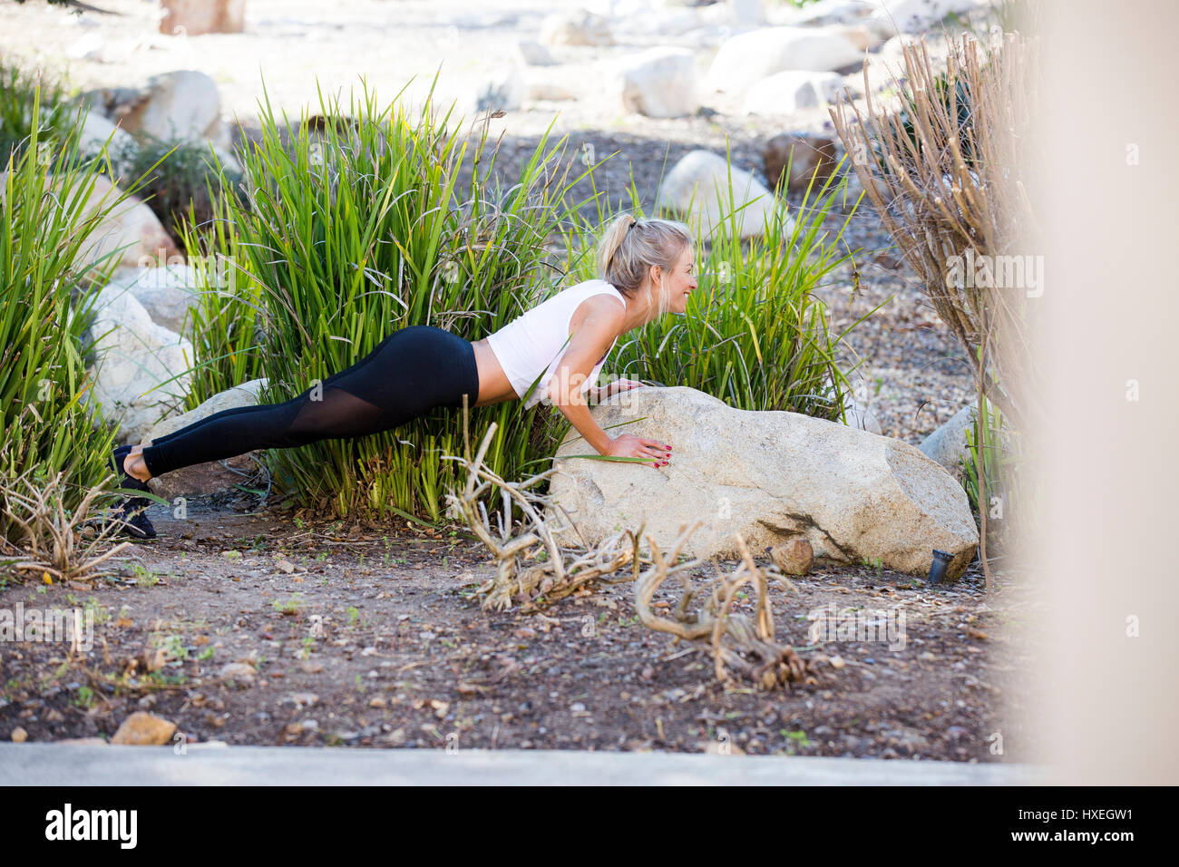 Una ragazza fa pushups su una roccia in una splendida piscina esterna e urbano. Foto Stock