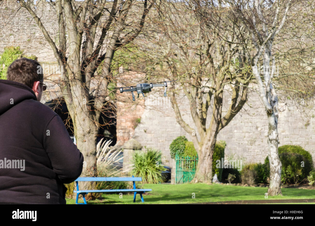 L'uomo battenti una radio controlled piccolo giocattolo drone in un parco. Conwy, Wales, Regno Unito, Gran Bretagna Foto Stock