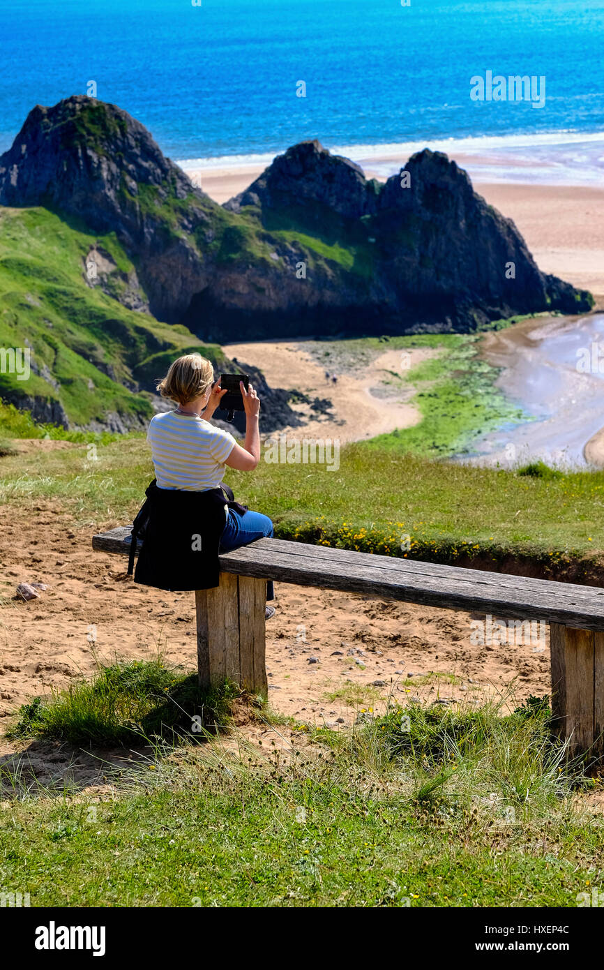 Tourist godendo la vista e scattare una foto al Three Cliffs Bay, Penisola di Gower, Galles del Sud Foto Stock
