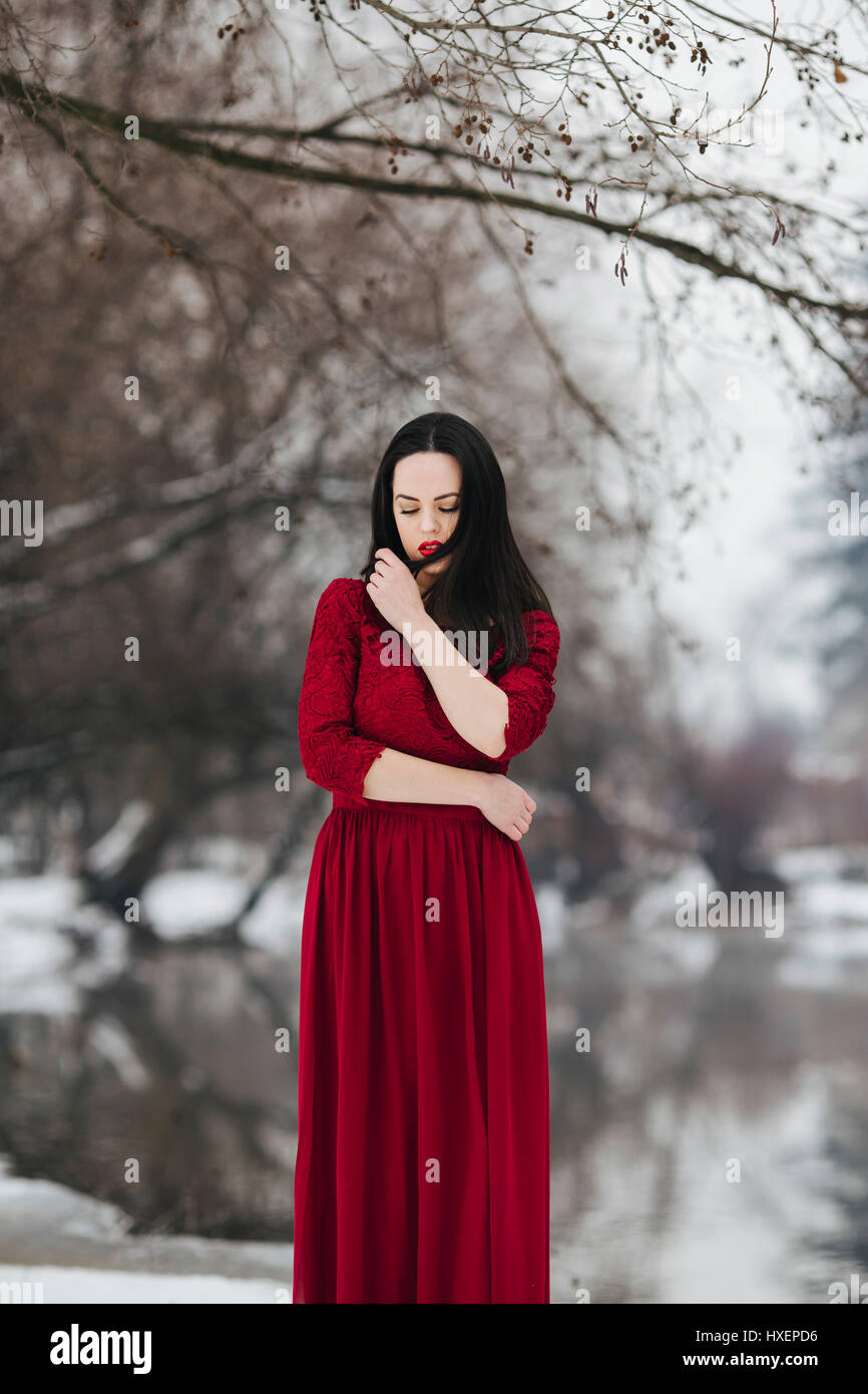 Donna in abito rosso in piedi nella neve Foto Stock