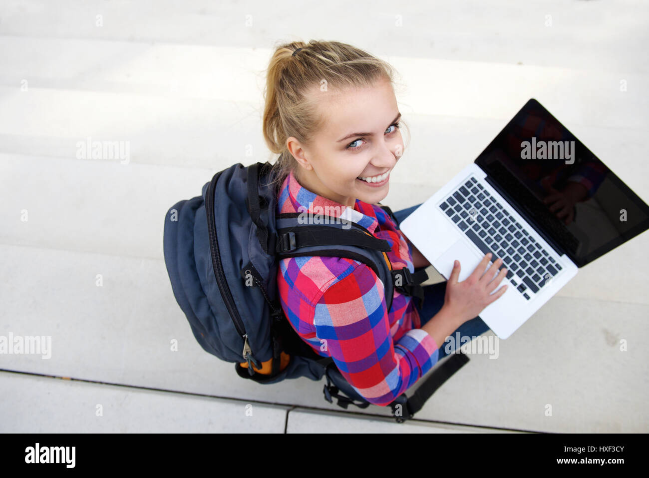 Ritratto da sopra sorridente studentessa seduta con il computer portatile Foto Stock