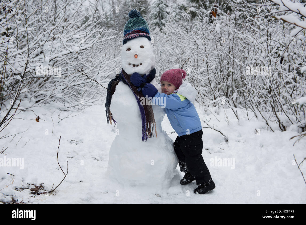Ritratto di ragazza carina rendendo pupazzo di neve sulla bella giornata nevosa Foto Stock