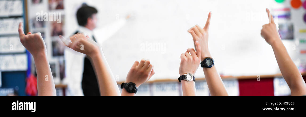 Tutti i bambini in aumento le mani per rispondere alle domande degli insegnanti Foto Stock