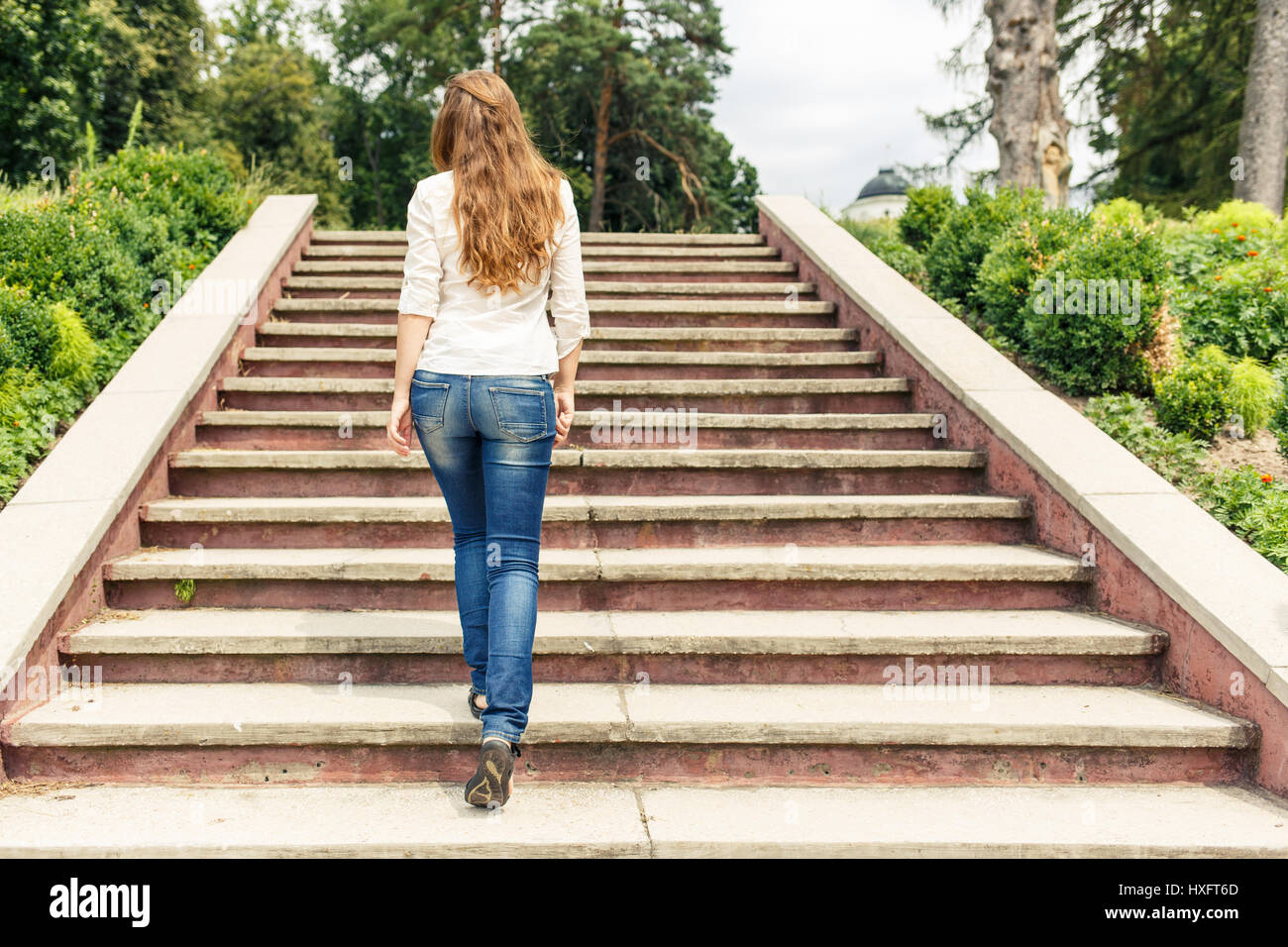 Vista posteriore del giovane donna salendo le scale nel parco Foto Stock