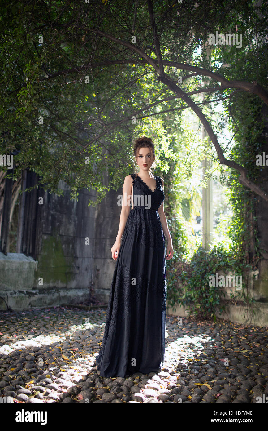 Ragazza che indossa un abito nero, in piedi dalla vecchia chiesa Foto Stock