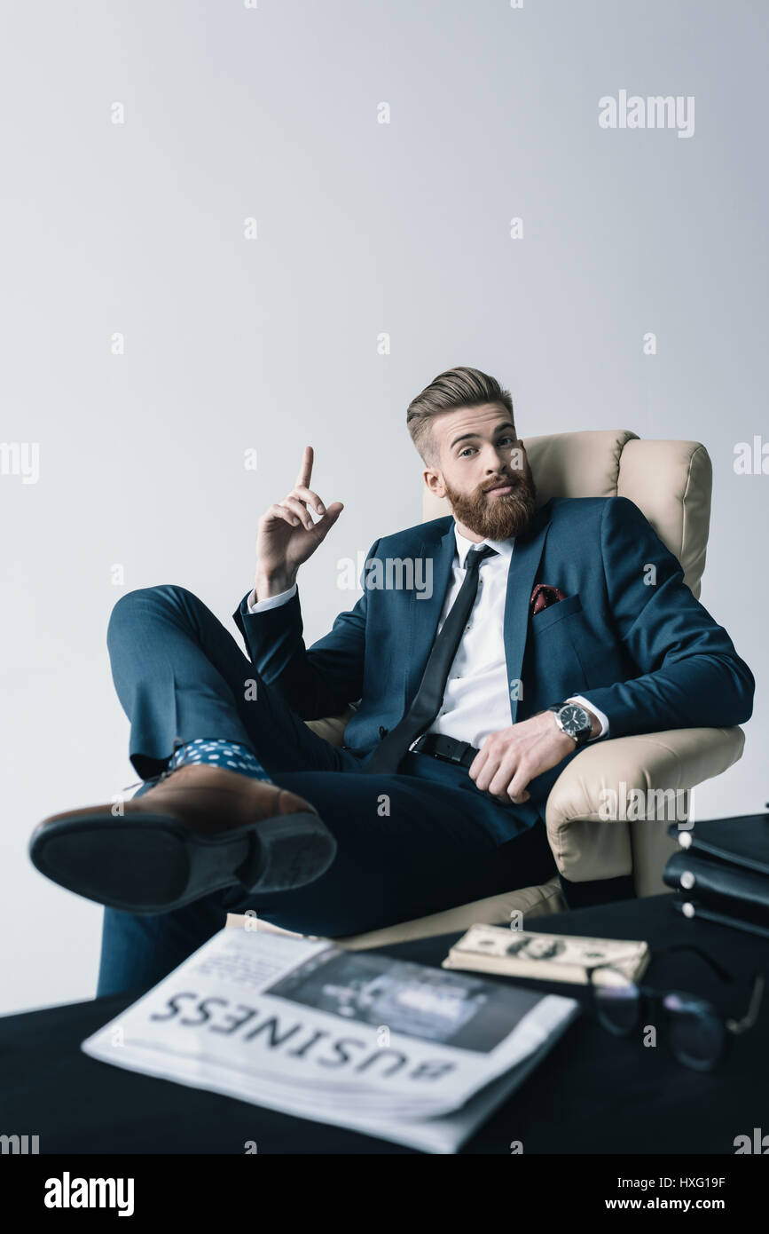 Imprenditore elegante seduto in poltrona in ufficio Foto Stock