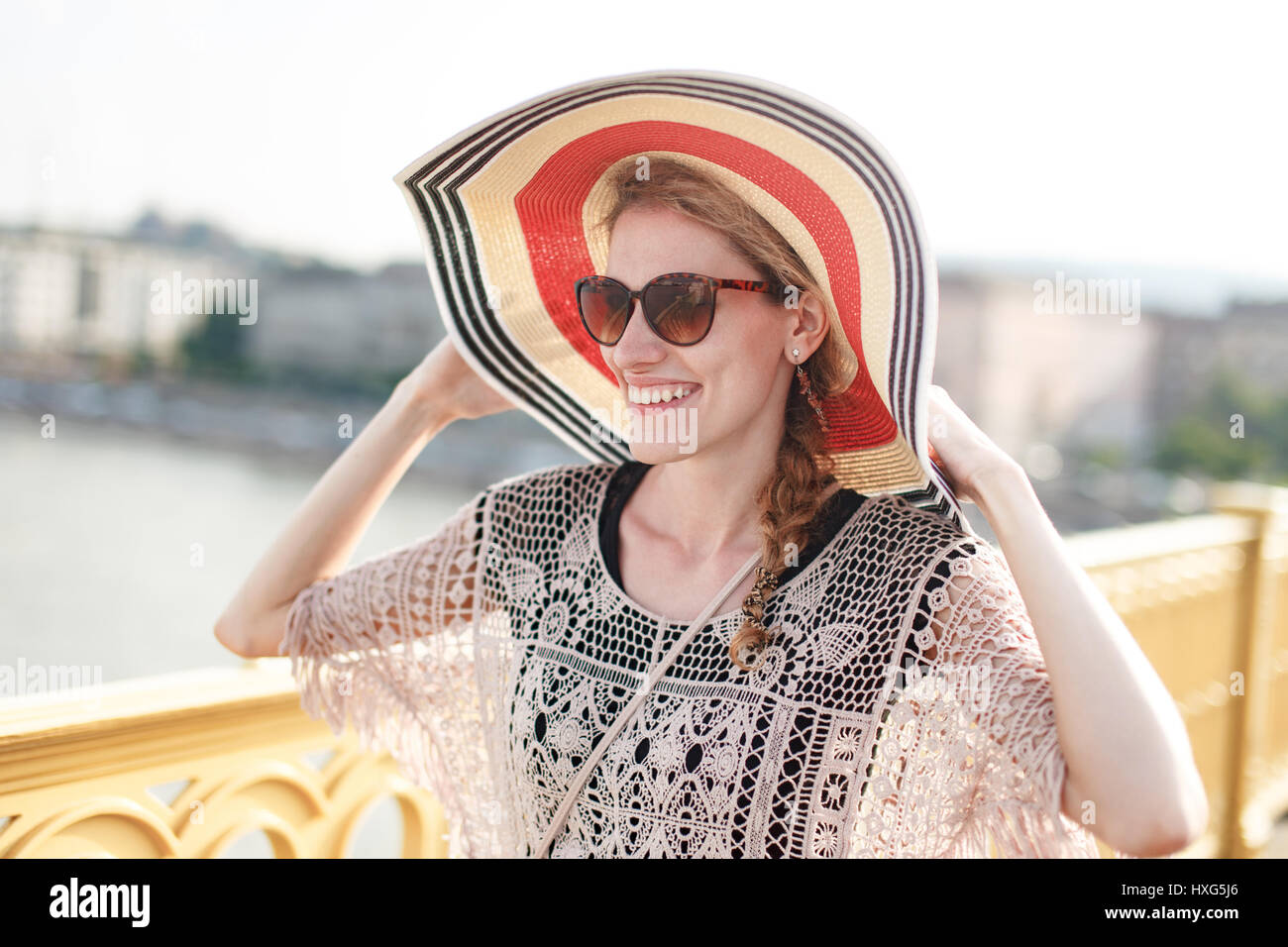 Felice giovane donna in hat camminando sul ponte e freschezza con denti sorriso, positività Foto Stock