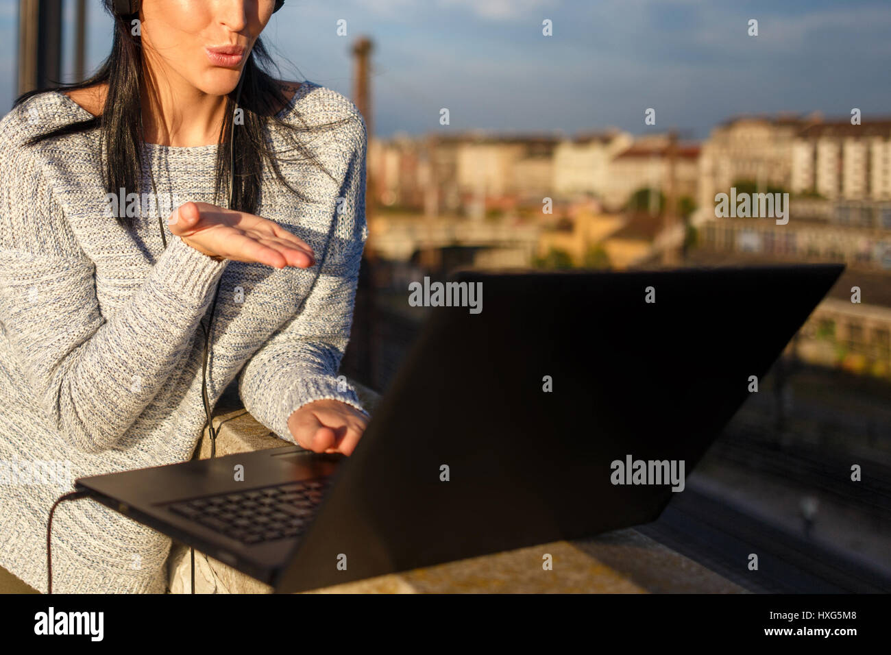 Giovane donna invio baci dal computer portatile outdoor closeup, tecnologia wireless Foto Stock