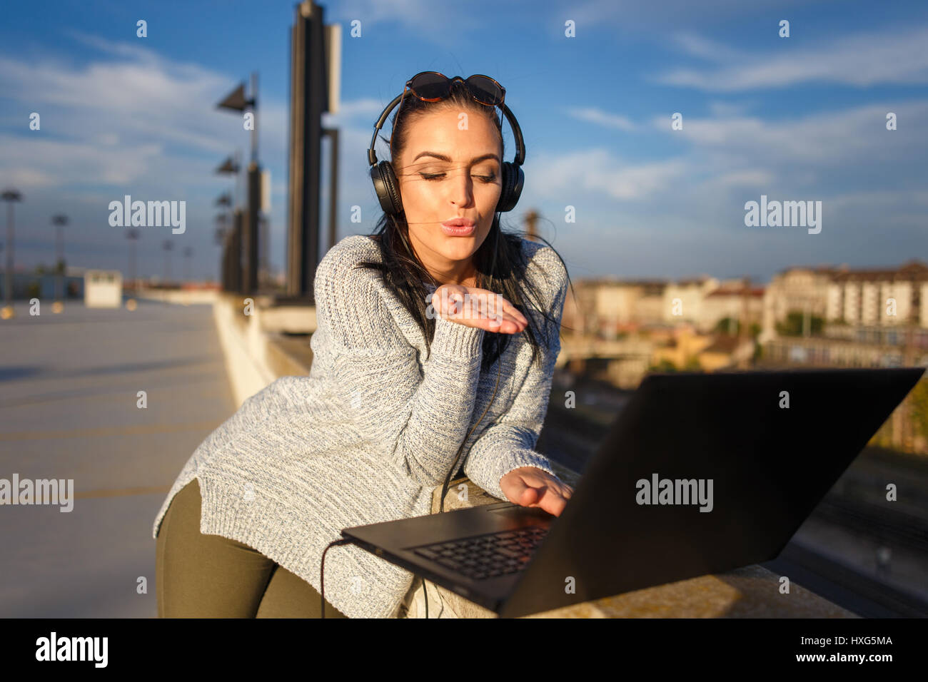Giovane donna caucasica invio baci da laptop all'aperto online Foto Stock