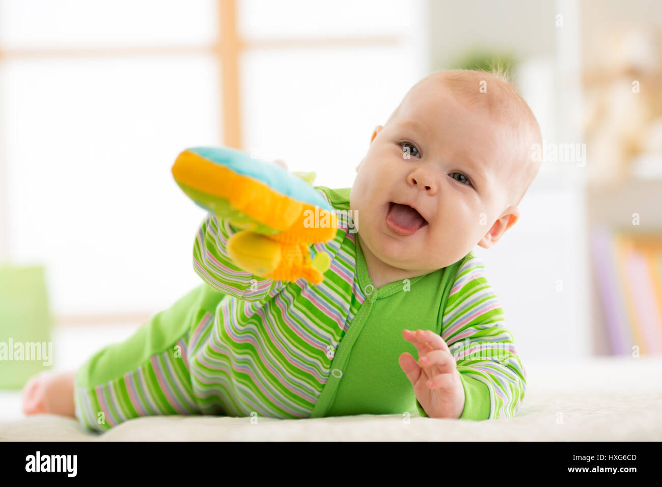 Il Bambino giacente sul suo ventre con toy su un letto di casa Foto Stock