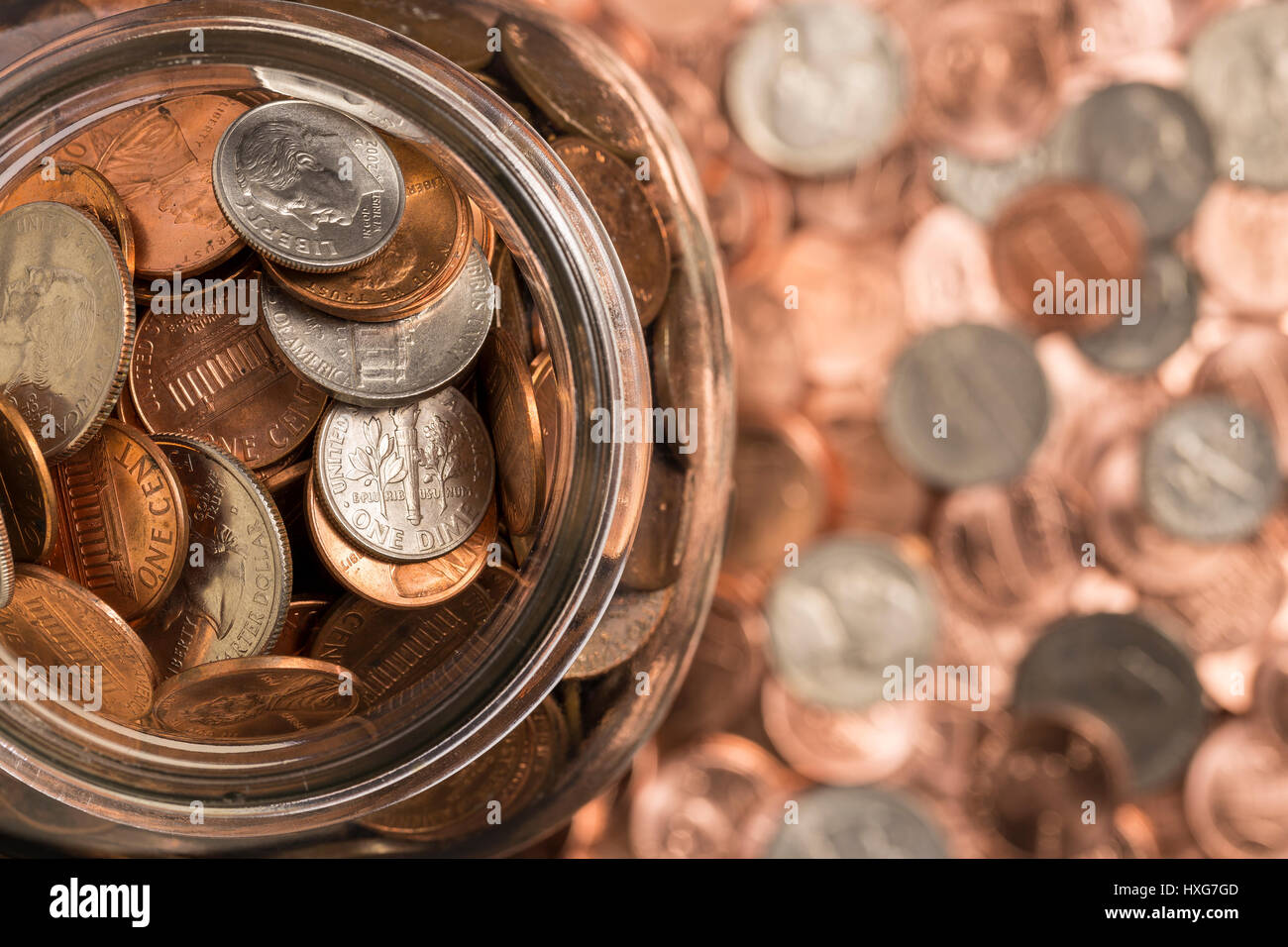 Coin Jar - Una vista da sopra di una moneta jar con monete in background. Foto Stock