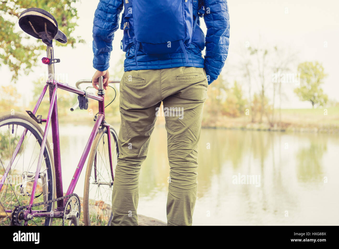 L'uomo con la bici da strada e guardando la vista sul fiume nel parco. Di " commuters " maschio e il pignone fisso della bicicletta relax nel verde del parco. Sport fitness motivazione e inspiratio Foto Stock