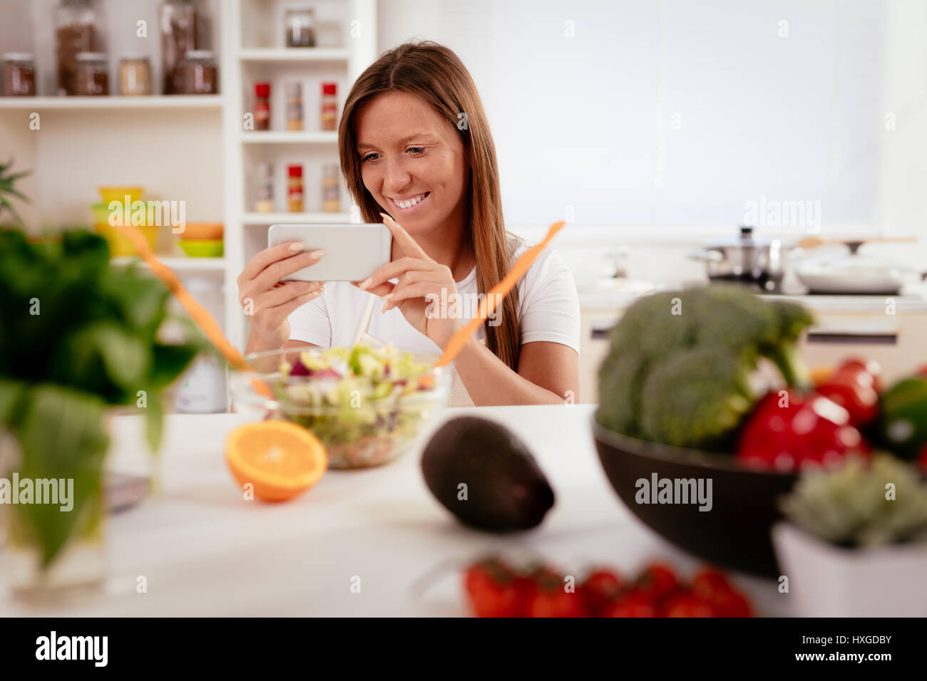 Bella giovane donna prendendo la foto di una sana insalata con smartphone per il suo blog. Foto Stock