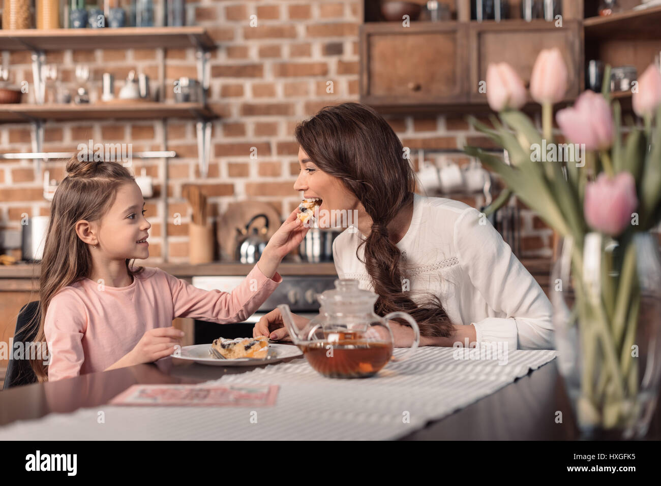 'Side View della figlia di madre di alimentazione con torta per la festa della mamma vacanze in cucina Foto Stock