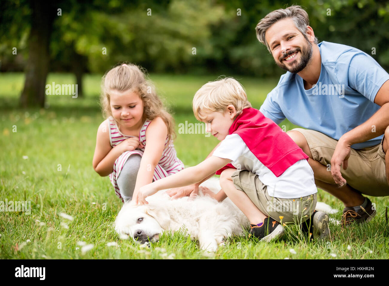 La famiglia felice giocare insieme con il cane in posizione di parcheggio Foto Stock