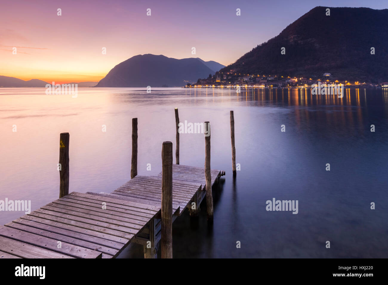 Un molo a Sulzano, davanti a Montisola e Peschiera Maraglio città durante un tramonto in inverno, provincia di Brescia, Lago d'Iseo, Lombardia, Italia. Foto Stock