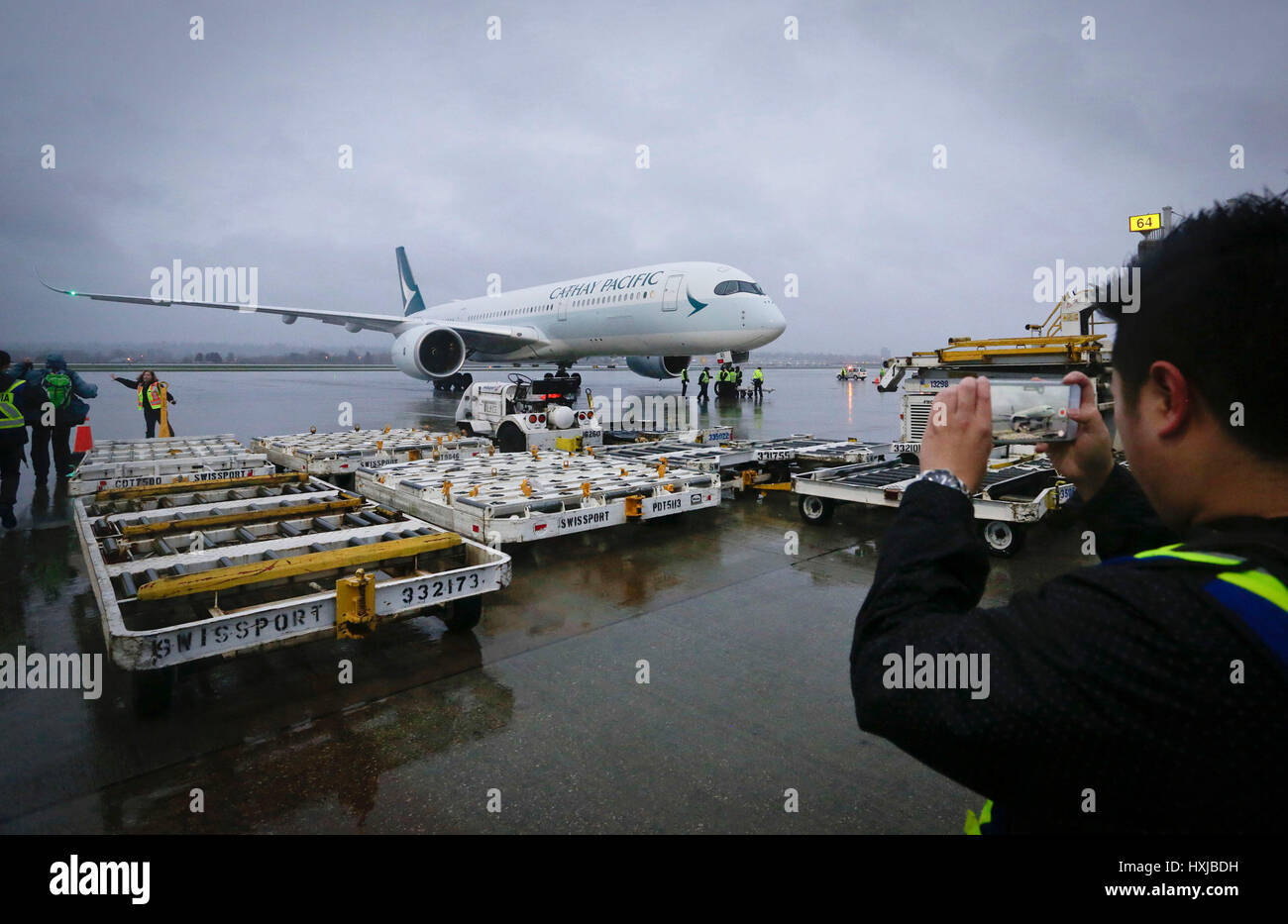 Vancouver, Canada. 28 Mar, 2017. Un aeroporto membro dello staff prende le immagini di un Airbus A350-900 jet del passeggero dopo il suo primo volo di linea per il Canada a Vancouver in Canada, il 28 marzo 2017. Un nuovo Airbus A350-900 jet del passeggero ha effettuato il suo primo volo di linea per il Canada il martedì ed ha cominciato a Cathay Pacific di utilizzare il piano per la sua Vancouver-Hong Kong rotta. Credito: Liang Sen/Xinhua/Alamy Live News Foto Stock